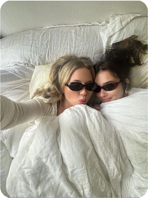 Two friends relaxing together in white bedding